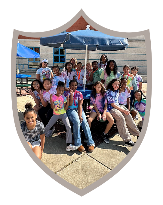 Group of students sitting at picnic table smiling outside of Lincoln Charter School Foundation.